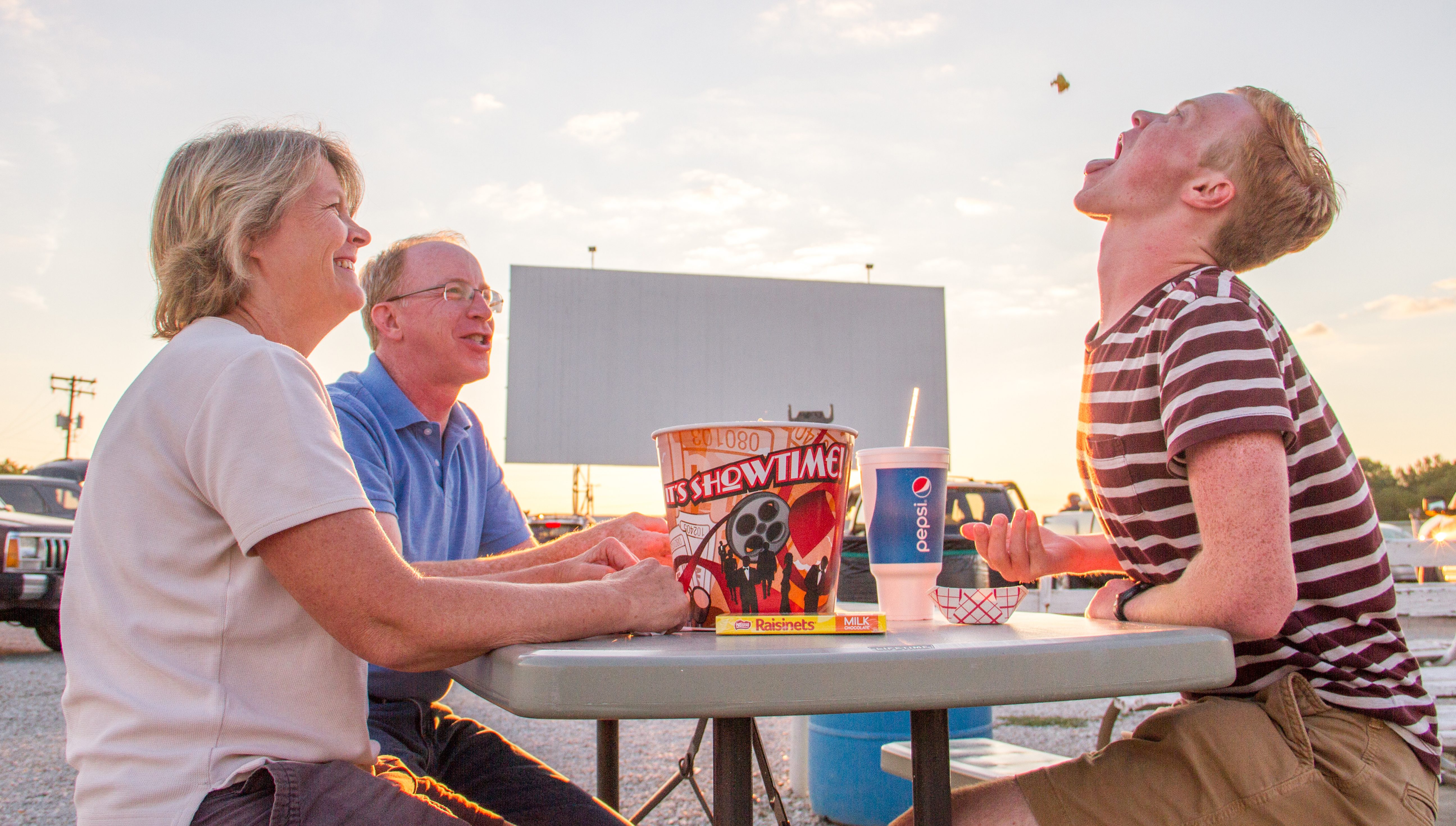 Family eating popcorn outside the drive-in.