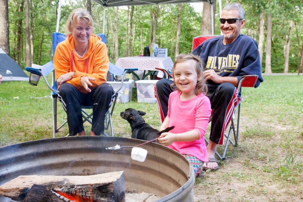 Family and dog around a campfire ring at the primitive campground.