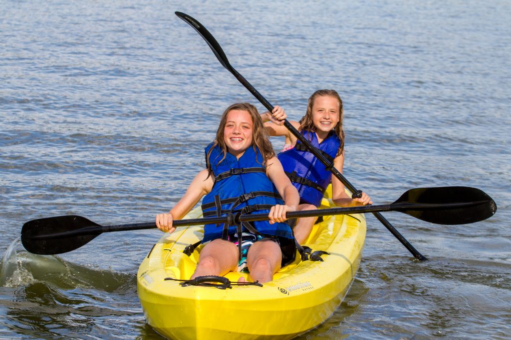 Two girls paddle a yellow kayak.