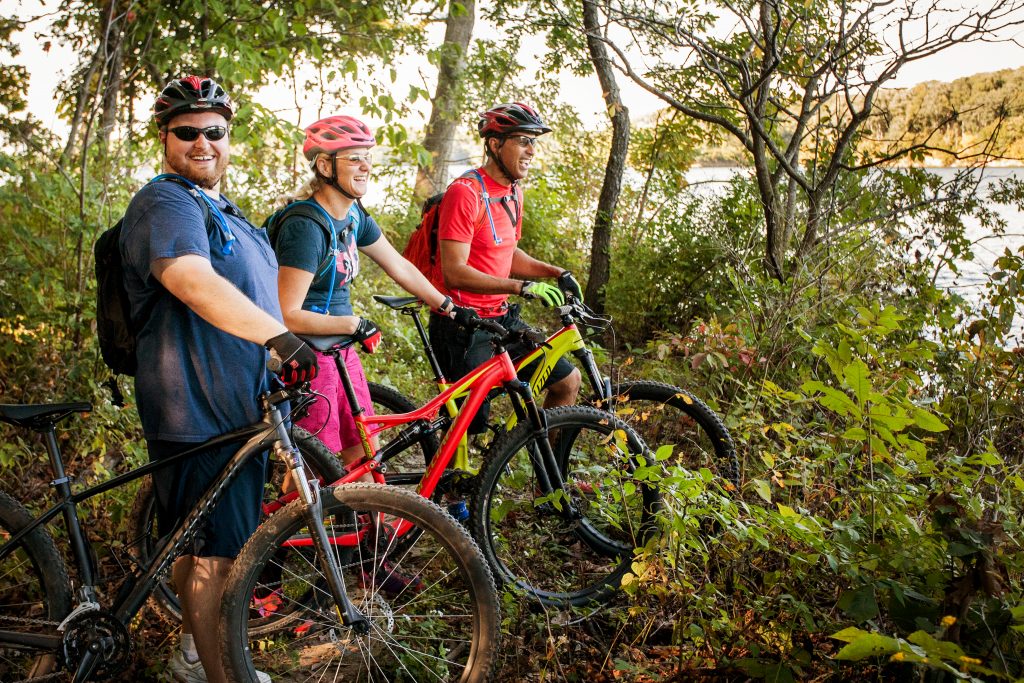 Three mountain bikers on the trail looking out over the lake.