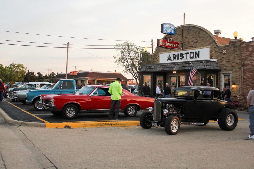 An image of the Ariston Cafe with classic cars